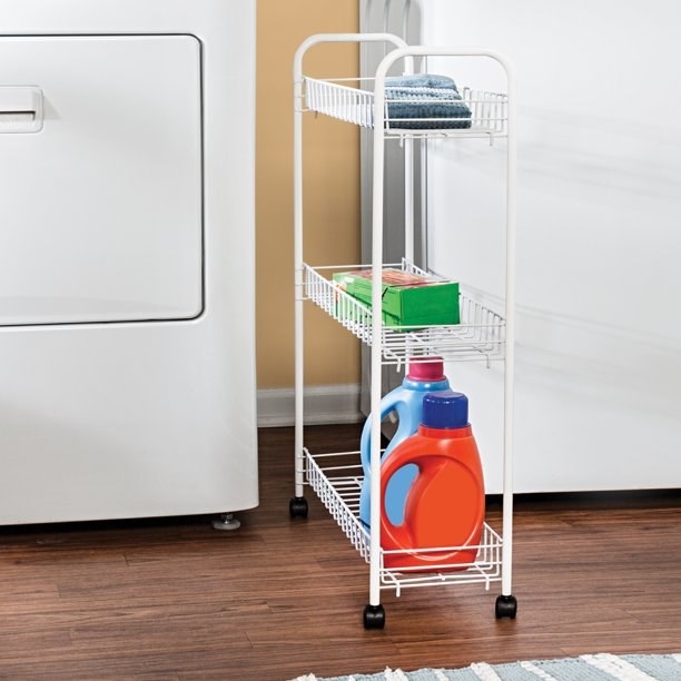 white wire three tier rolling cart in between a washing machine and dryer