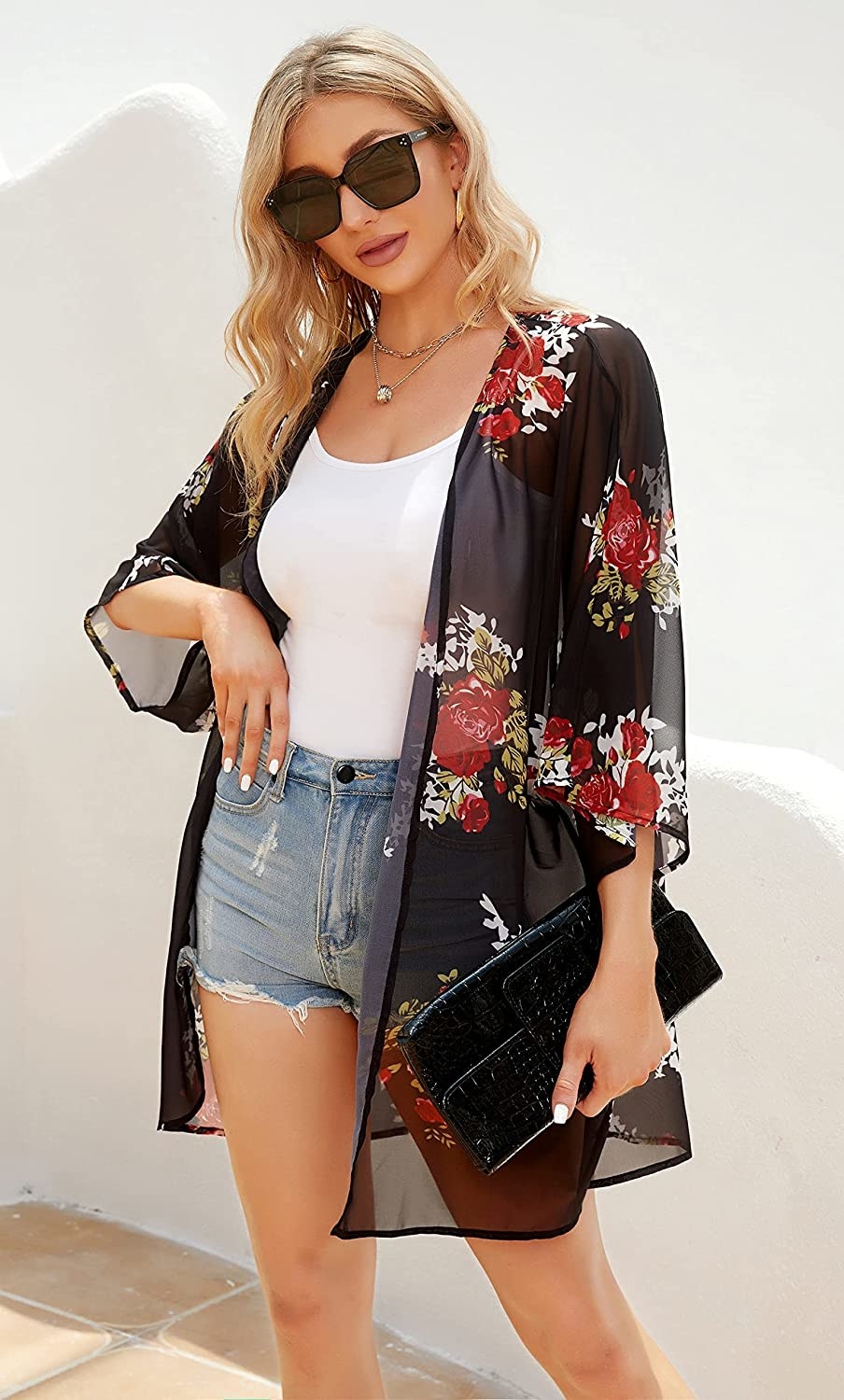 model wearing black sheer flowy cardigan with a floral print over a white tank top