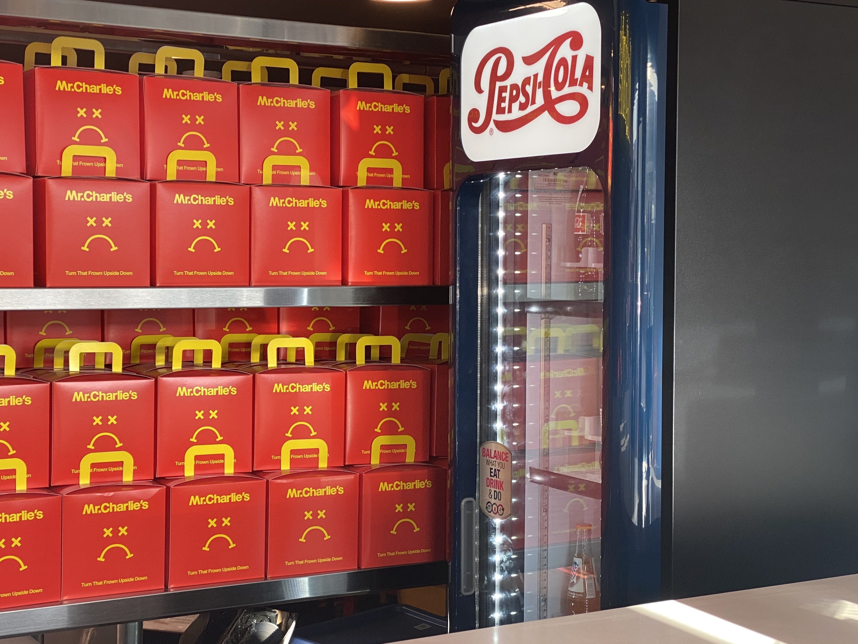 stacked boxes on a shelf next to a vintage Pepsi-Cola sign