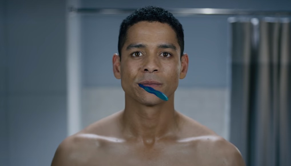 Alan stands in his bathroom, a blue toothbrush in his mouth