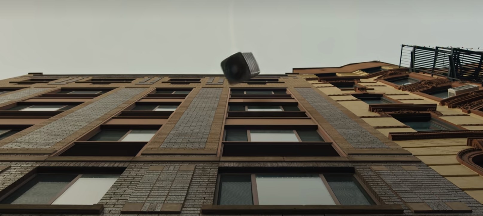 An A/C unit falls off a building towards the camera