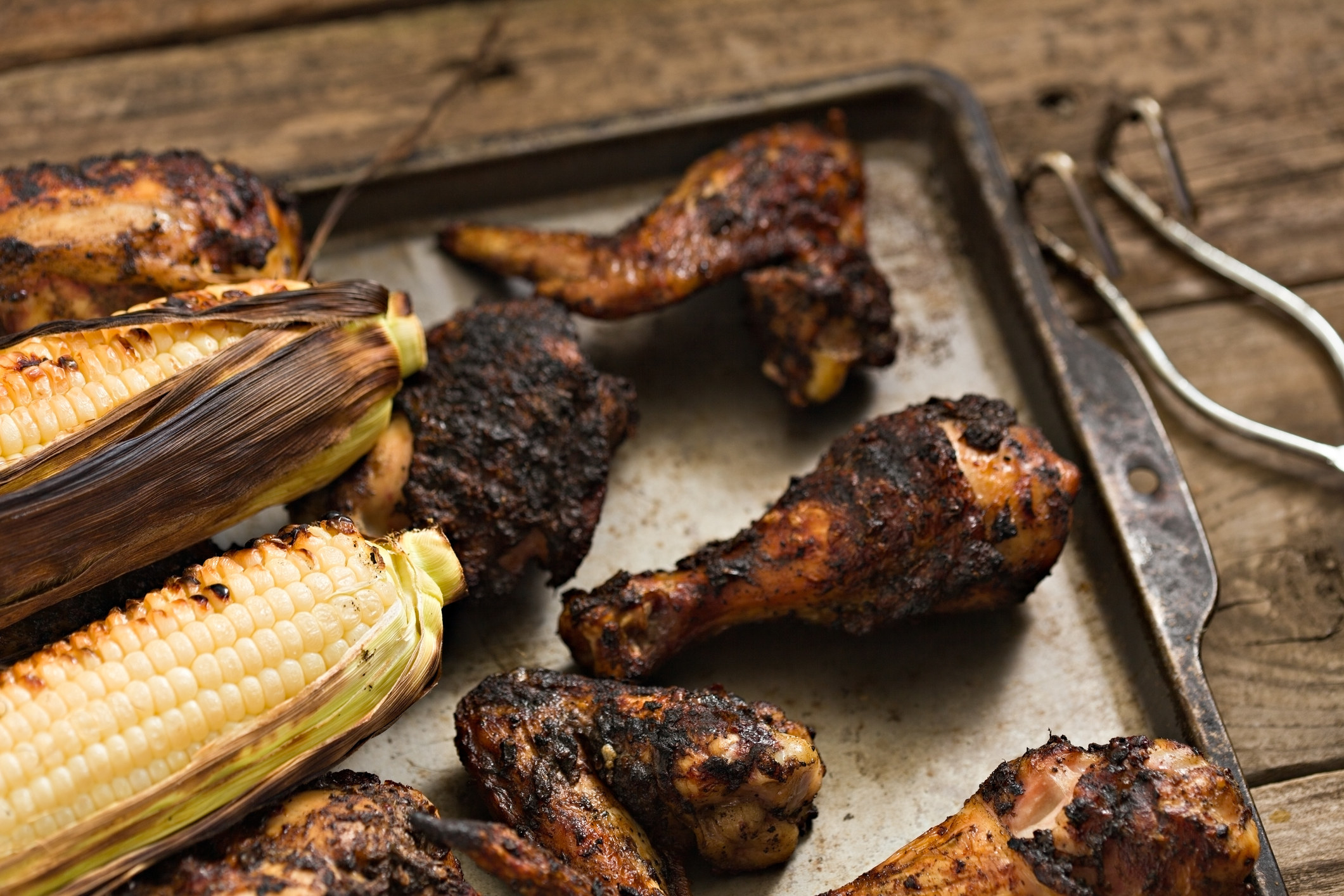 A plate of blackened chicken and corn on the cob.