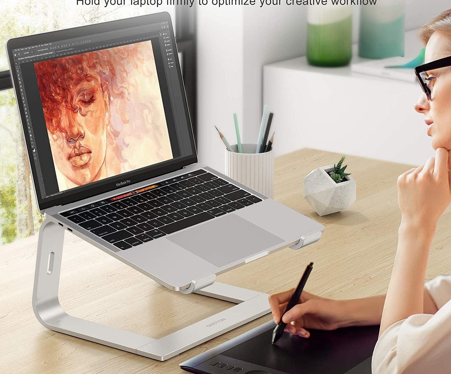 A person working on their laptop while it sits on the stand