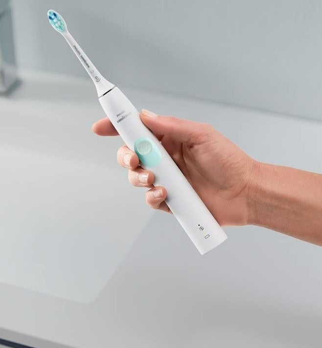 a person holding an electric toothbrush