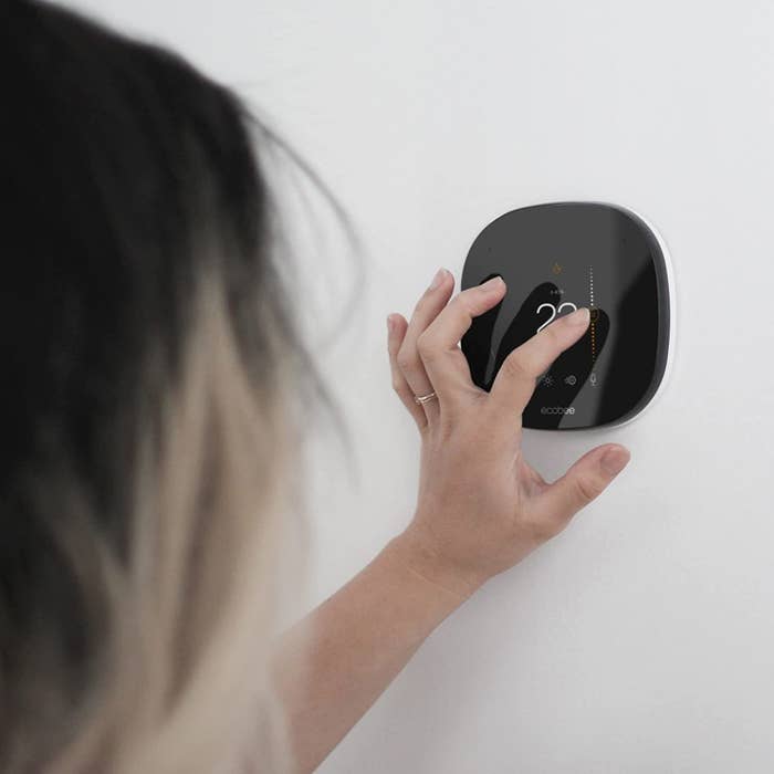a person adjusting the temperature on a wall-mounted thermostat