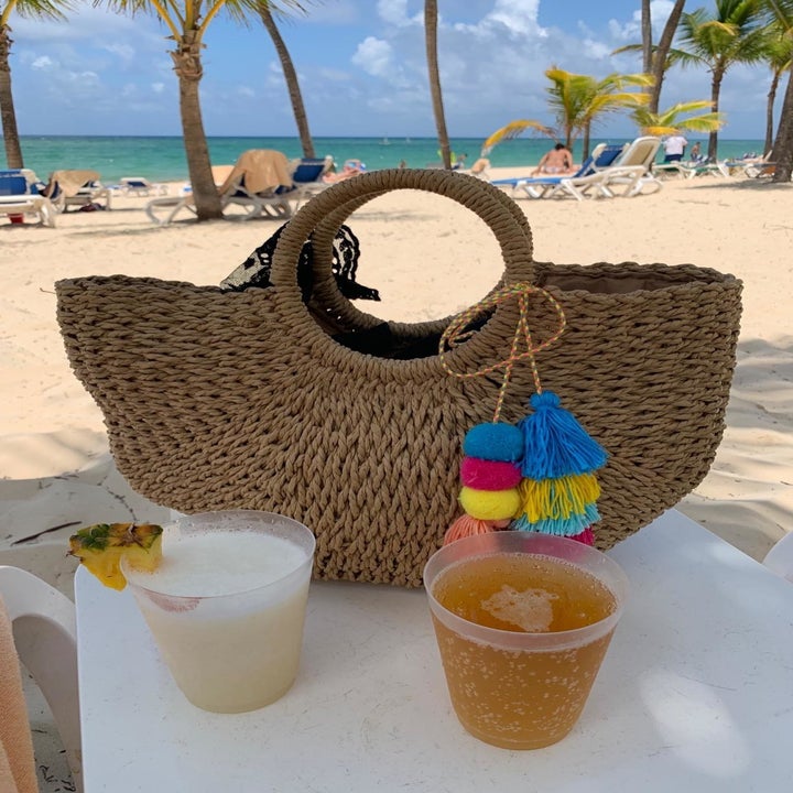 the purse next to two tropical drinks on a beach