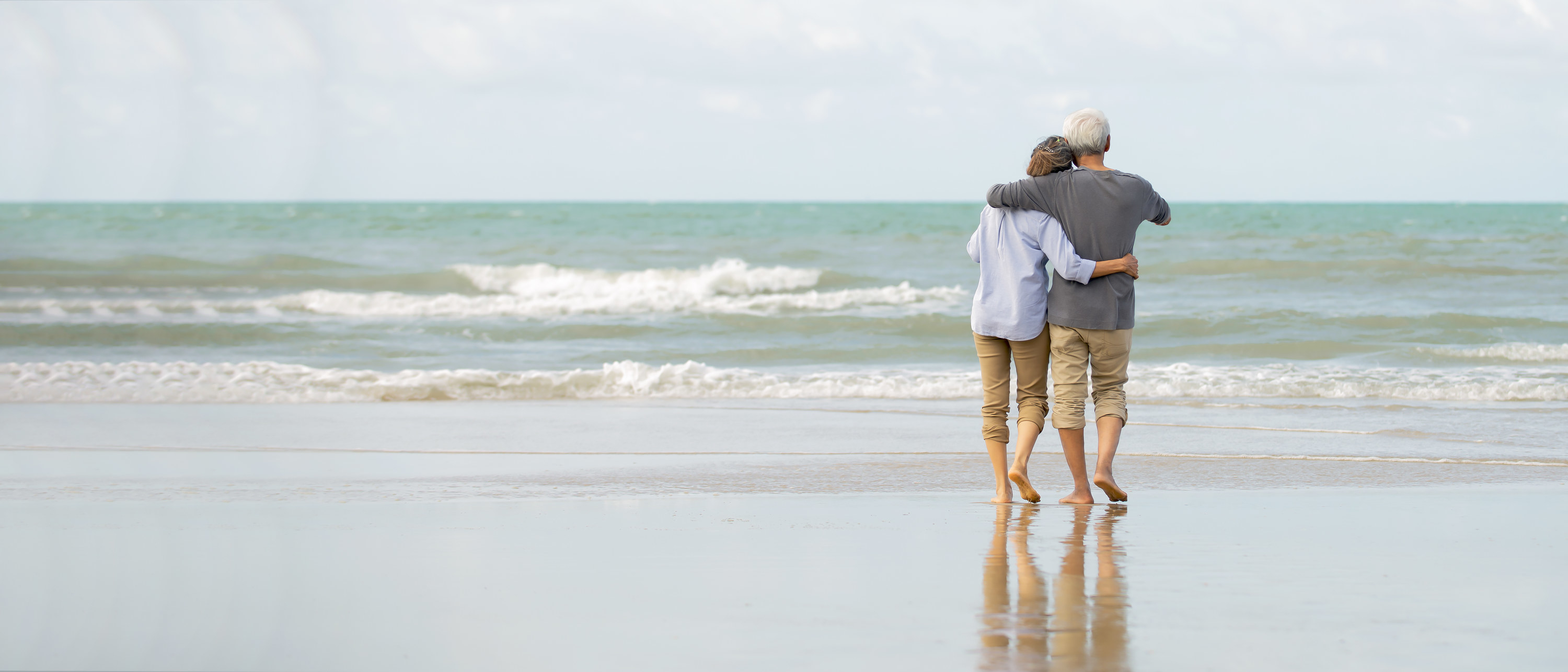 A couple hugging on the beach and looking at the water