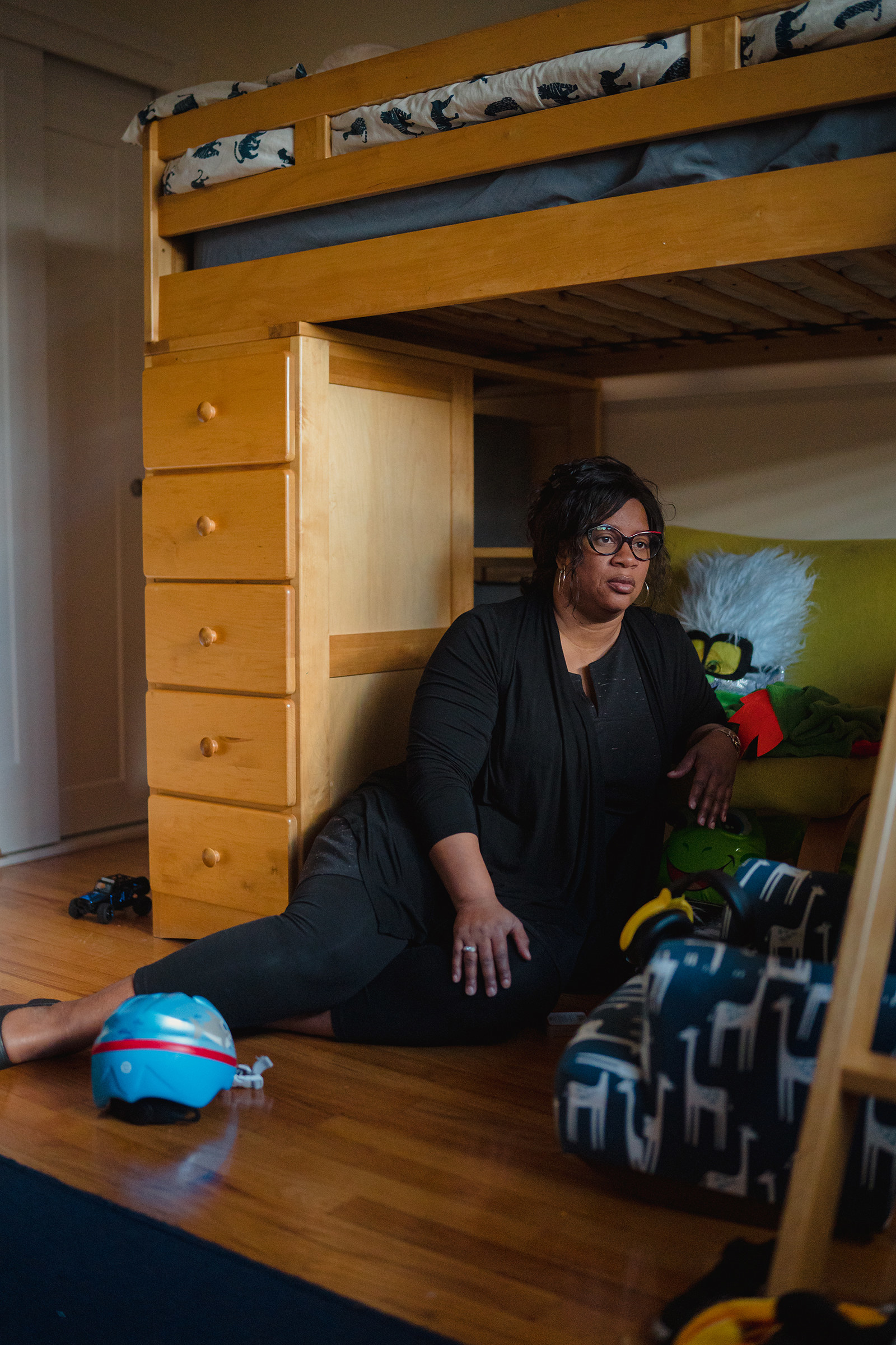 A woman wearing black sitting on the floor of a child&#x27;s room