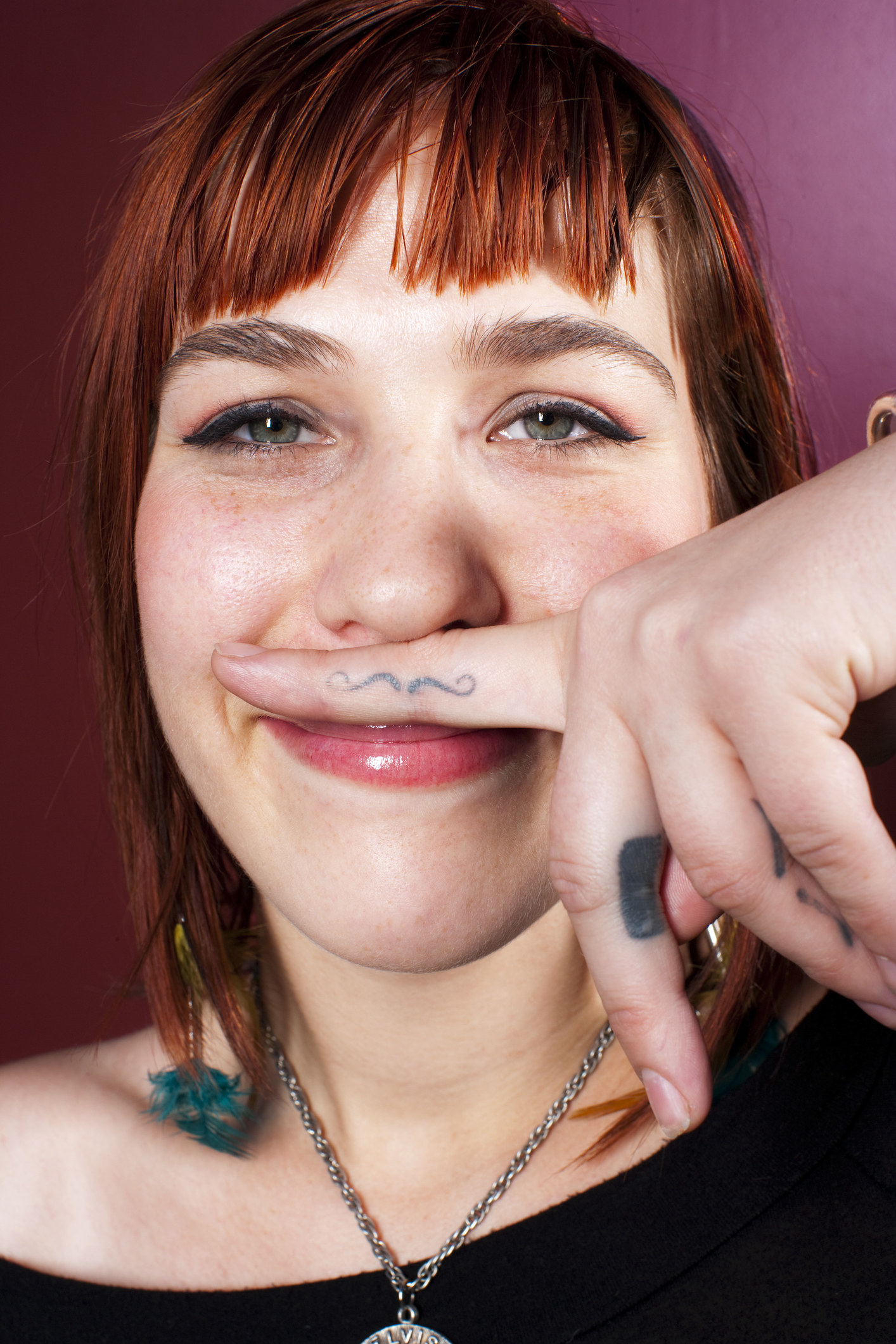 A woman holding her mustache finger tattoo to her face