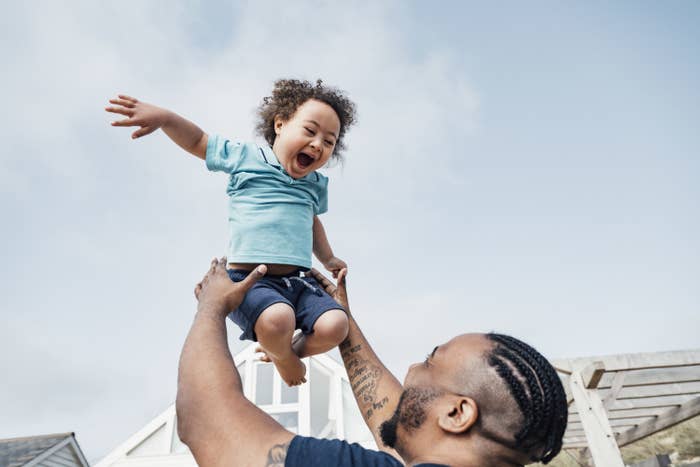 Person playing with a young child by holding them up in the air