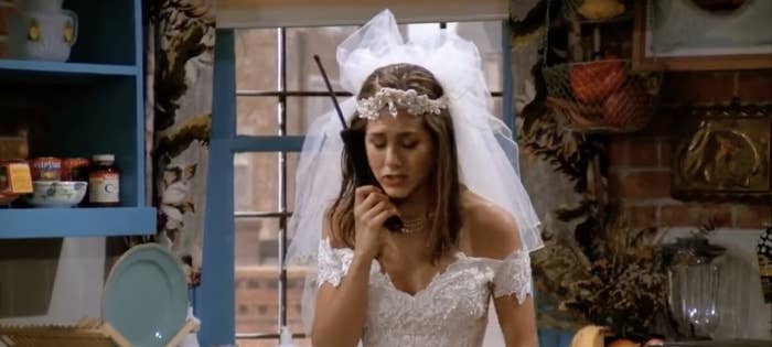 Rachel talks on the phone in her wedding dress