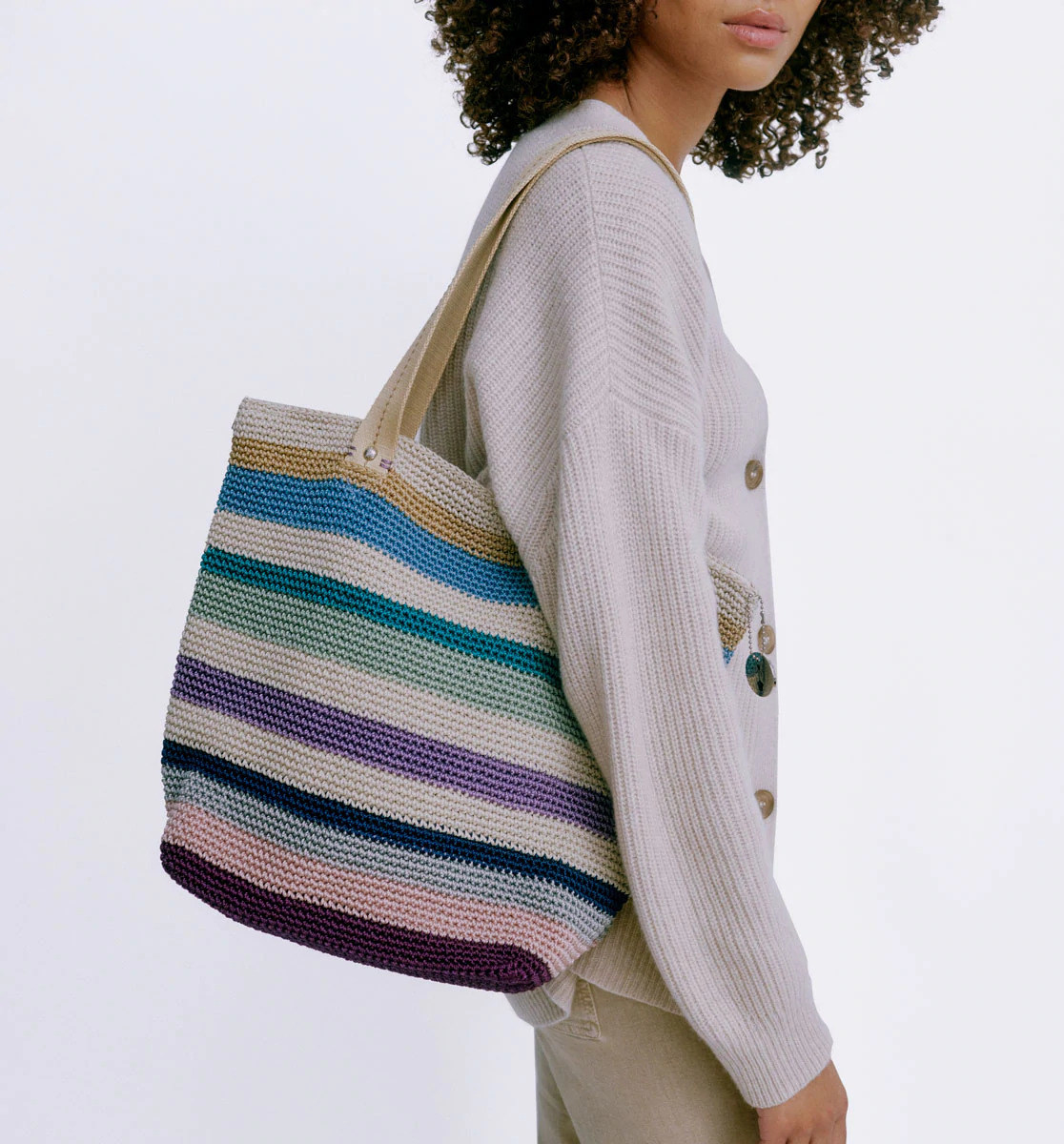 model with a multi colored striped tote bag with a recycled crochet exterior