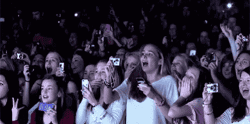 A crowd of young girls at a concert breaking out in cheers