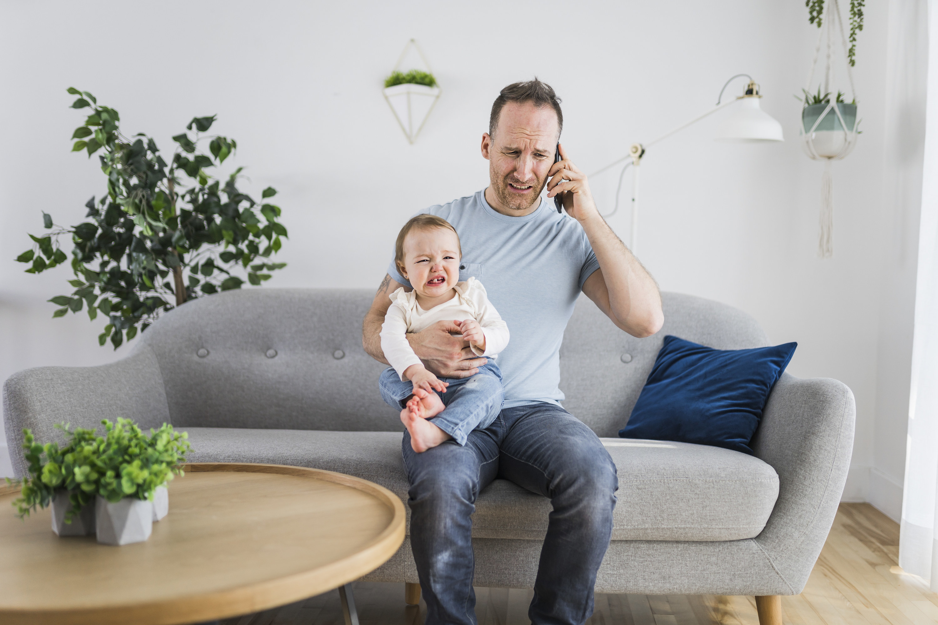 Dad yelling on phone while holding a baby