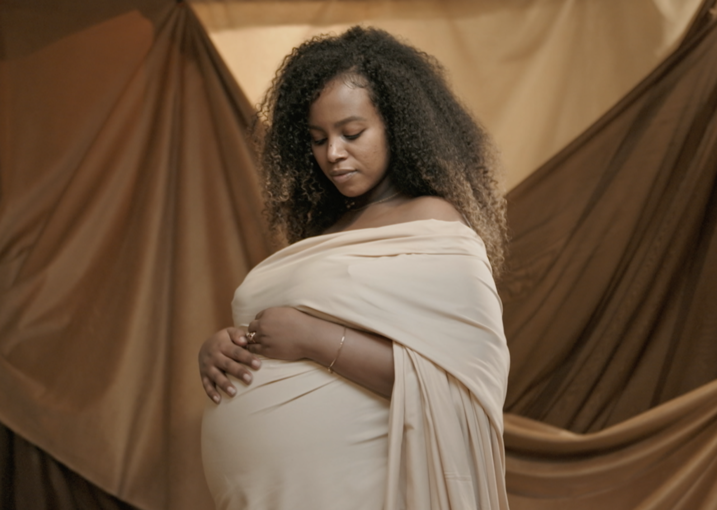 A screengrab of a Black, pregnant woman modeling in the Queen Collective documentary surrounding Black maternal health