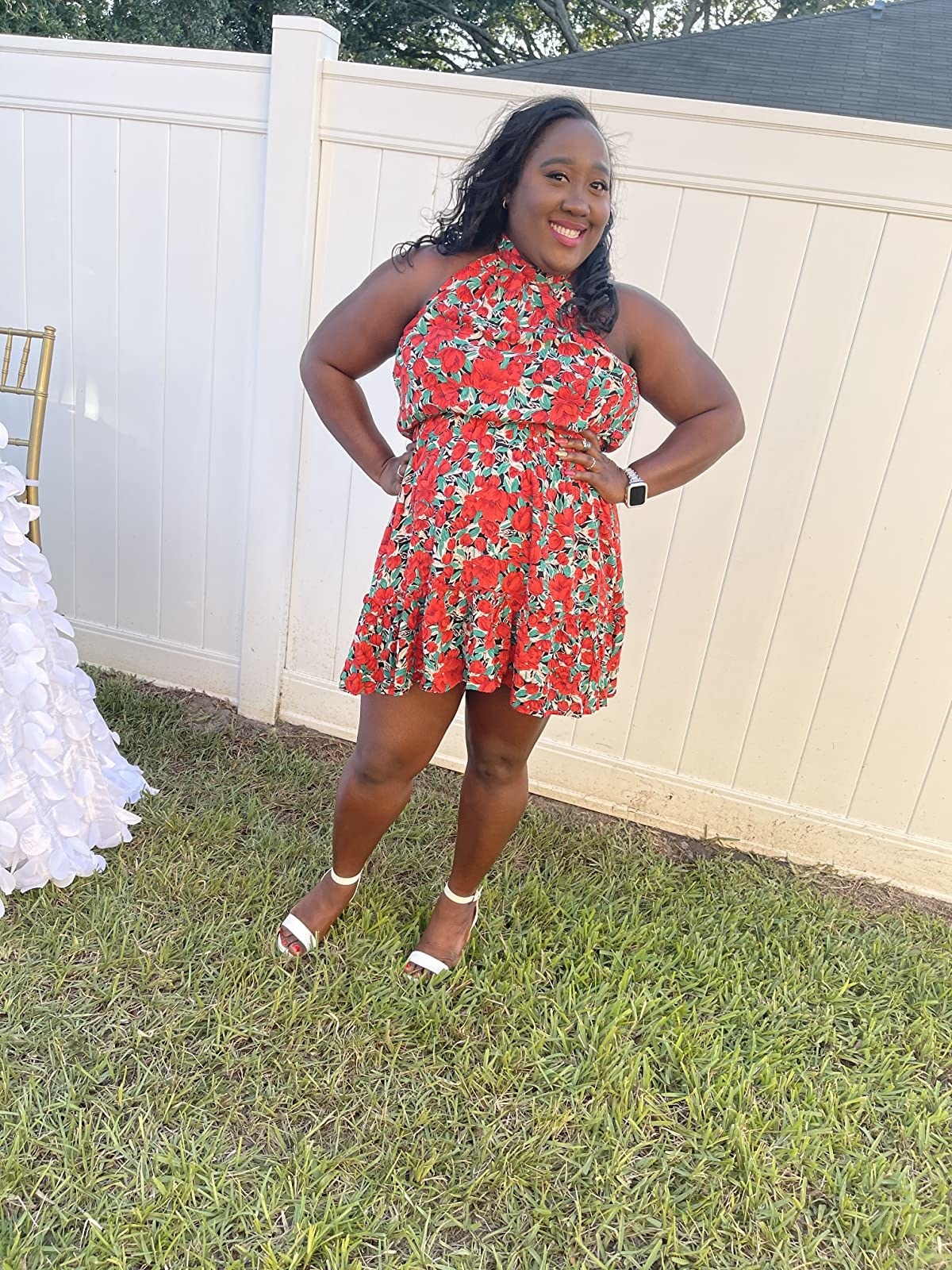 reviewer wearing red floral print halter neck dress with a ruffled hem