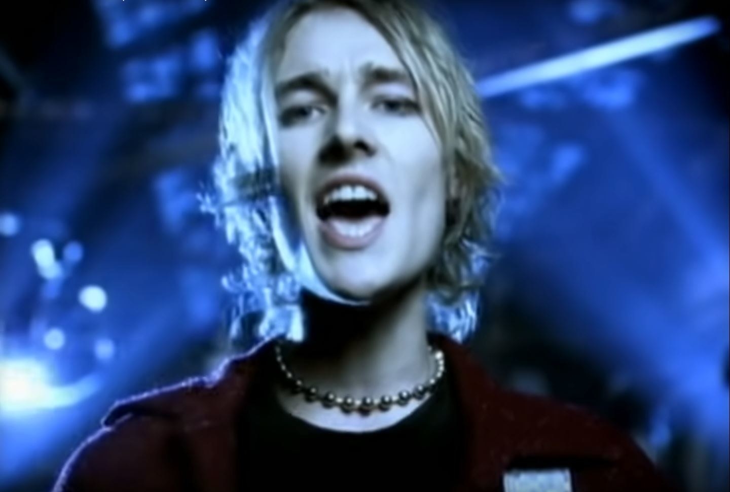 A young Daniel Johns singing against a blue background