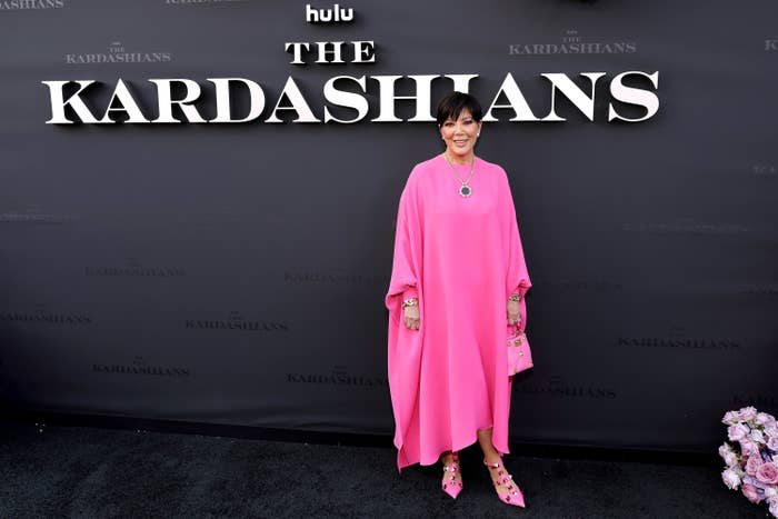 Kris Jenner standing in front of &quot;The Kardashians&quot; logo.