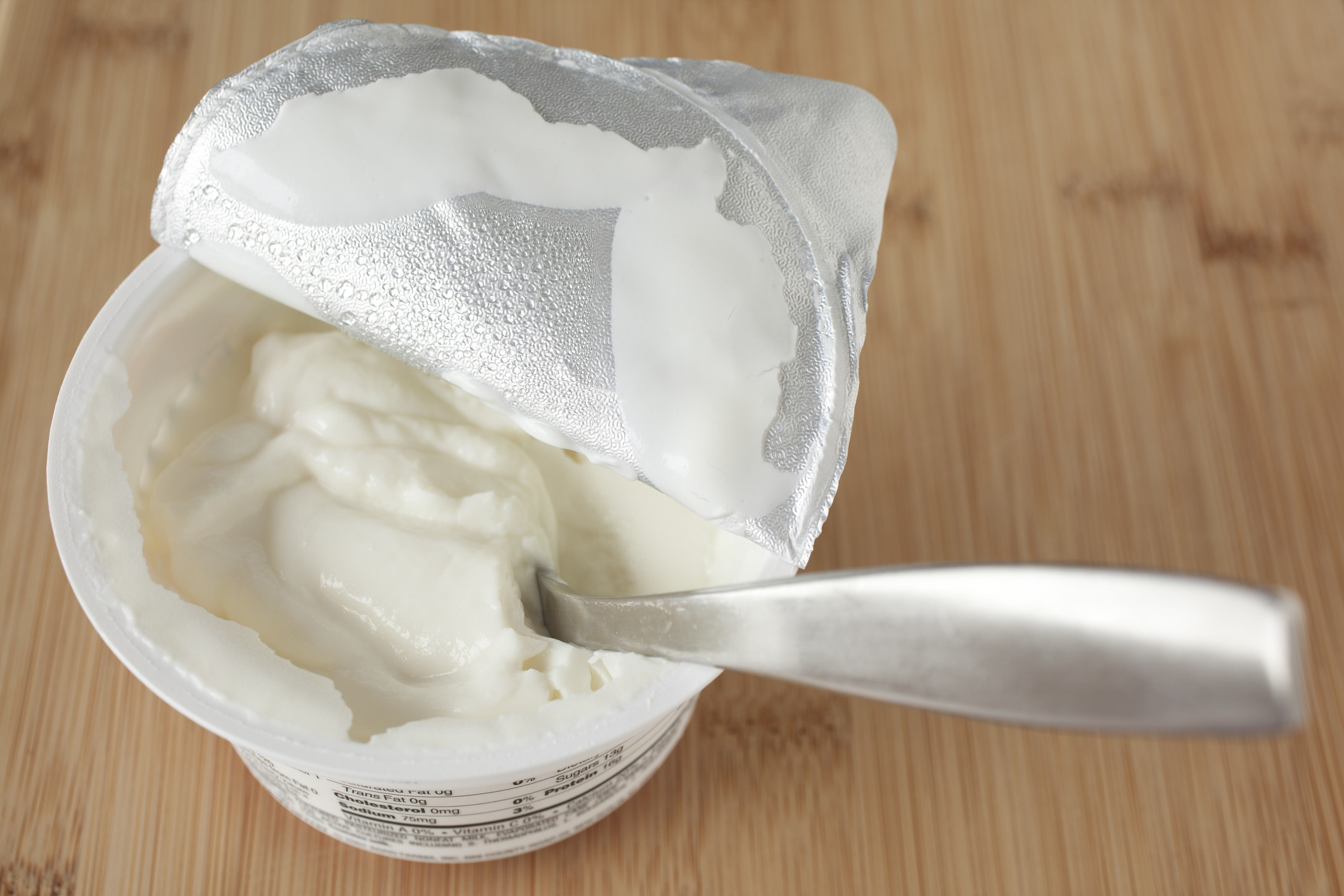 A small container of greek yogurt with a spoon in it