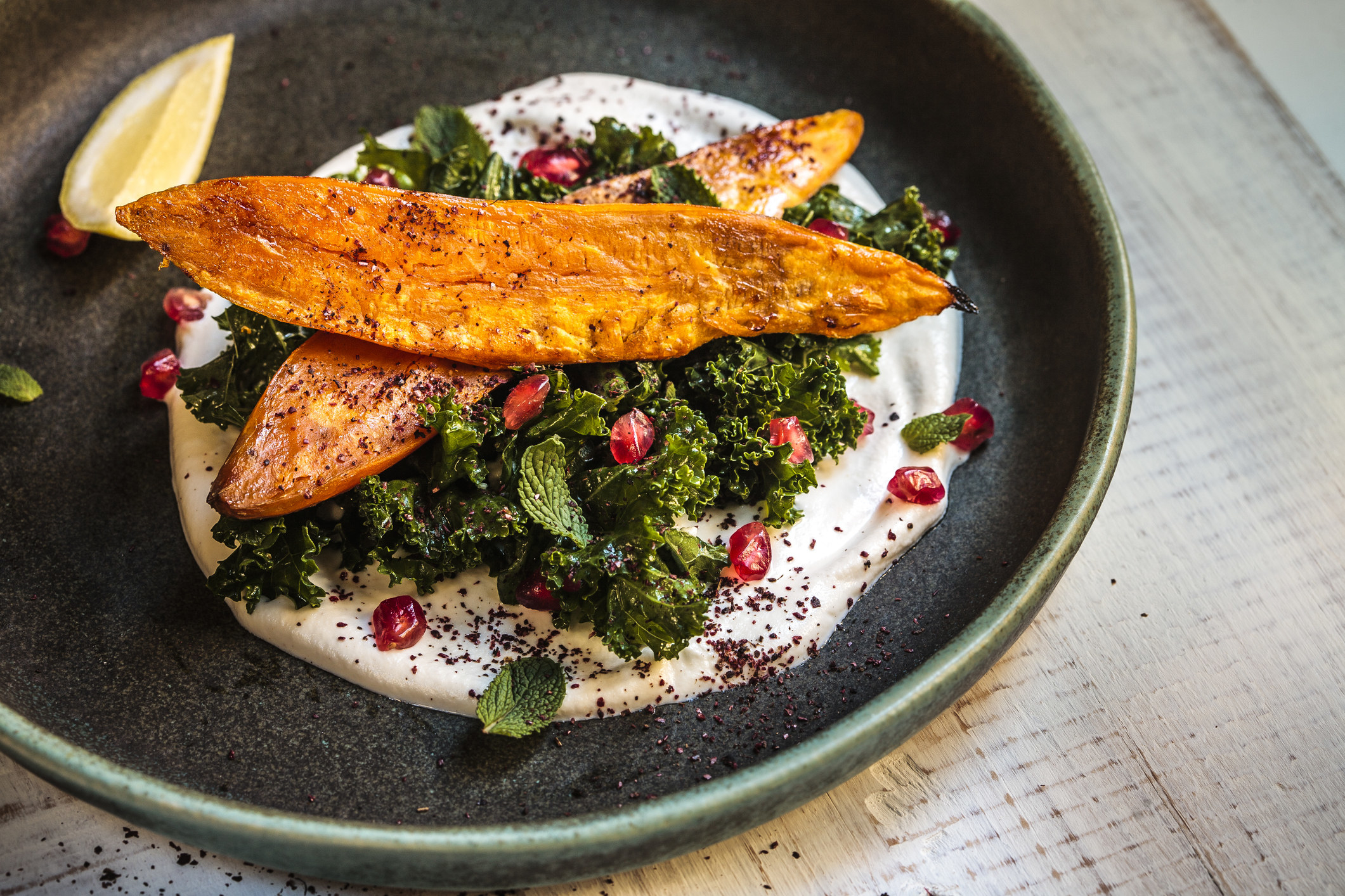 Sweet potatoes and kale over yogurt sauce with sumac and spices.
