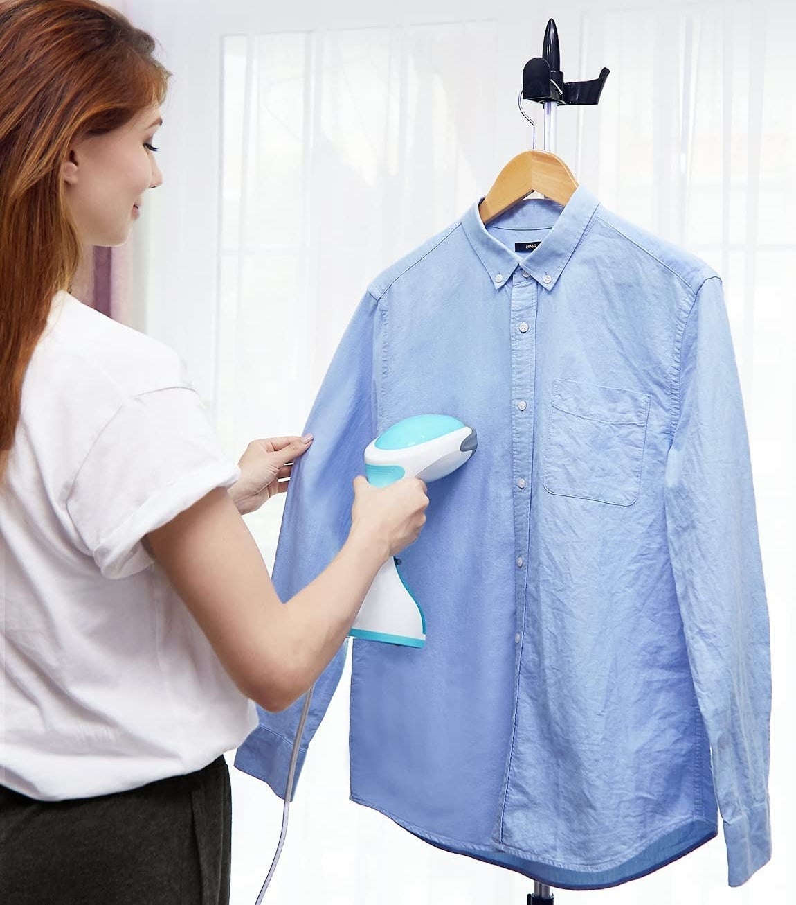 a person using the steamer to steam a button down shirt