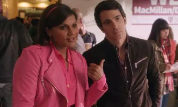 Mindy wears a brightly colored jacket over a matching shirt and Danny wears a dark jacket
