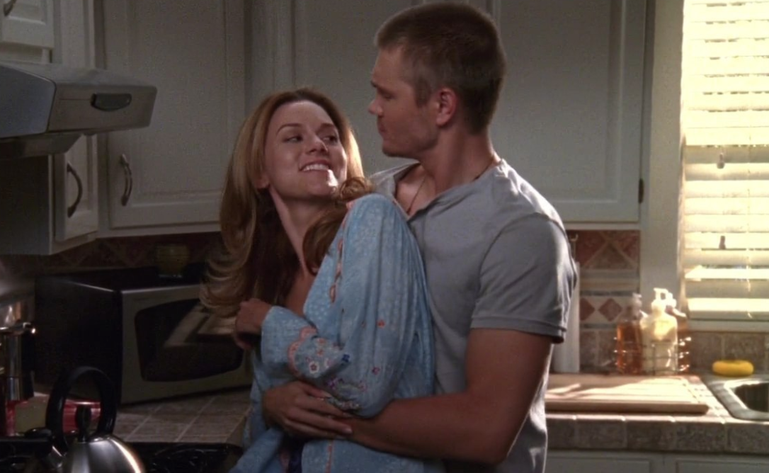 Lucas holds Peyton from behind as they stand in their kitchen