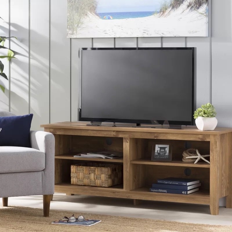 A brown TV stand with books and frames and storage cube