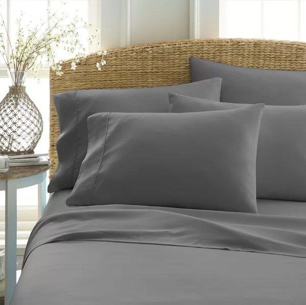 Gray sheet set on a bed with a woven wicker headboard