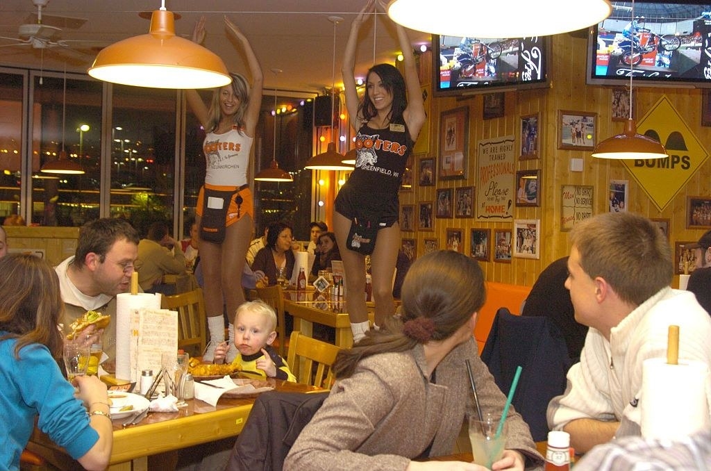 Hooters girls dancing on tables in front of customers.