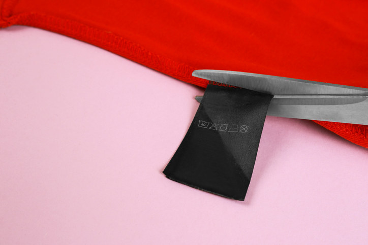 A closeup of scissors cutting the tag of an article of clothing