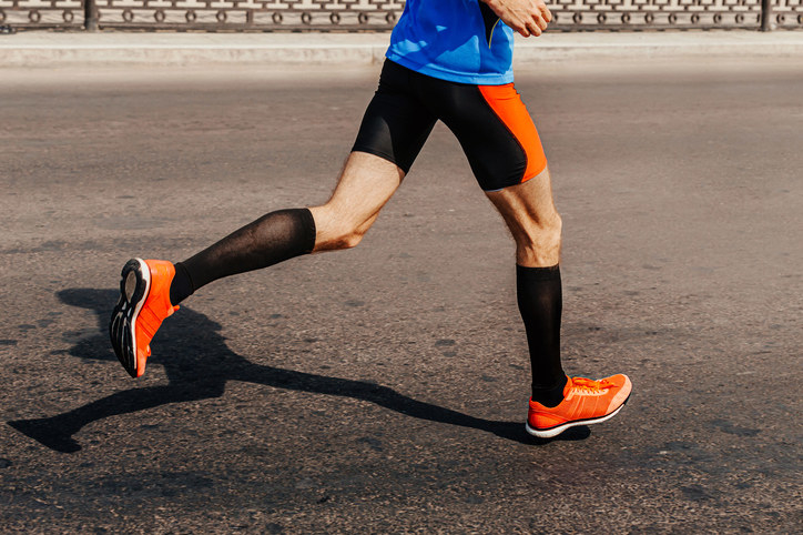 A man in running attire wearing black compression socks