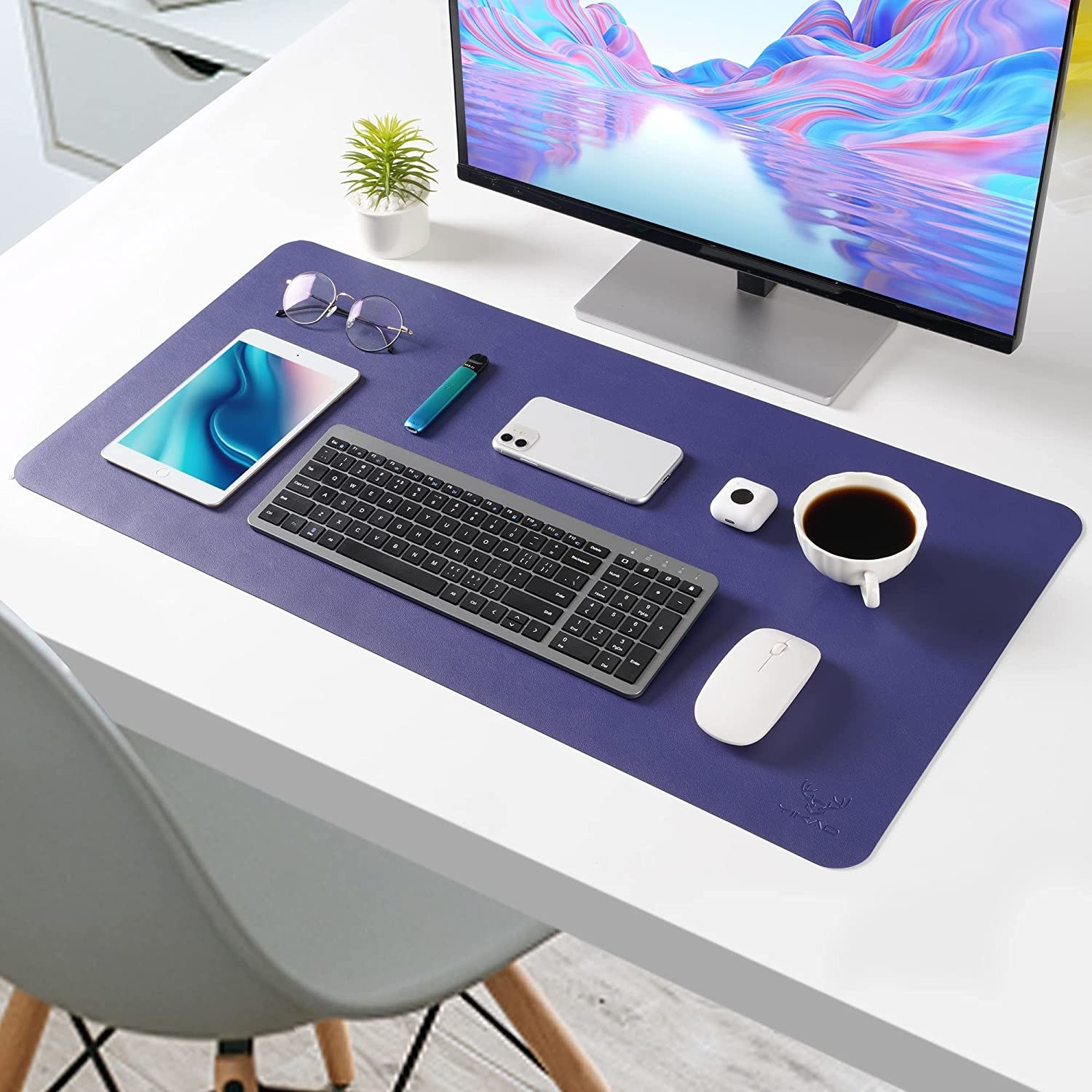 The desk pad with a several tech gadgets and a cup of coffee on it