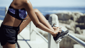A woman in running attire tying her running shoe.