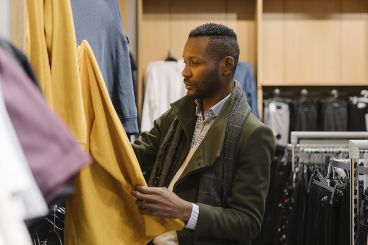 A man looking at clothing in a store.