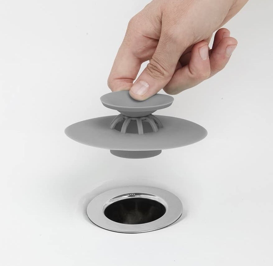 a person holding the hair-catching drain plug
