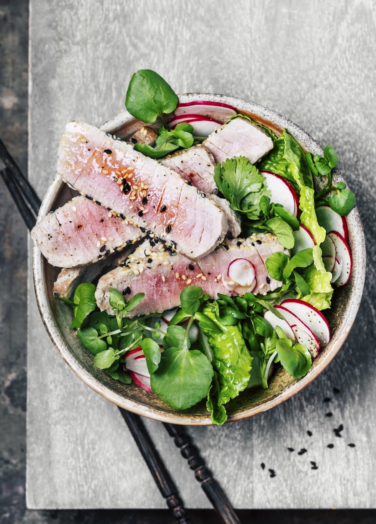 A bowl of salad with tuna steak.