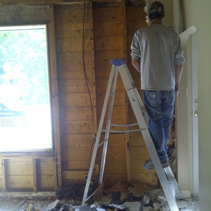 A man standing on a ladder doing home renovations