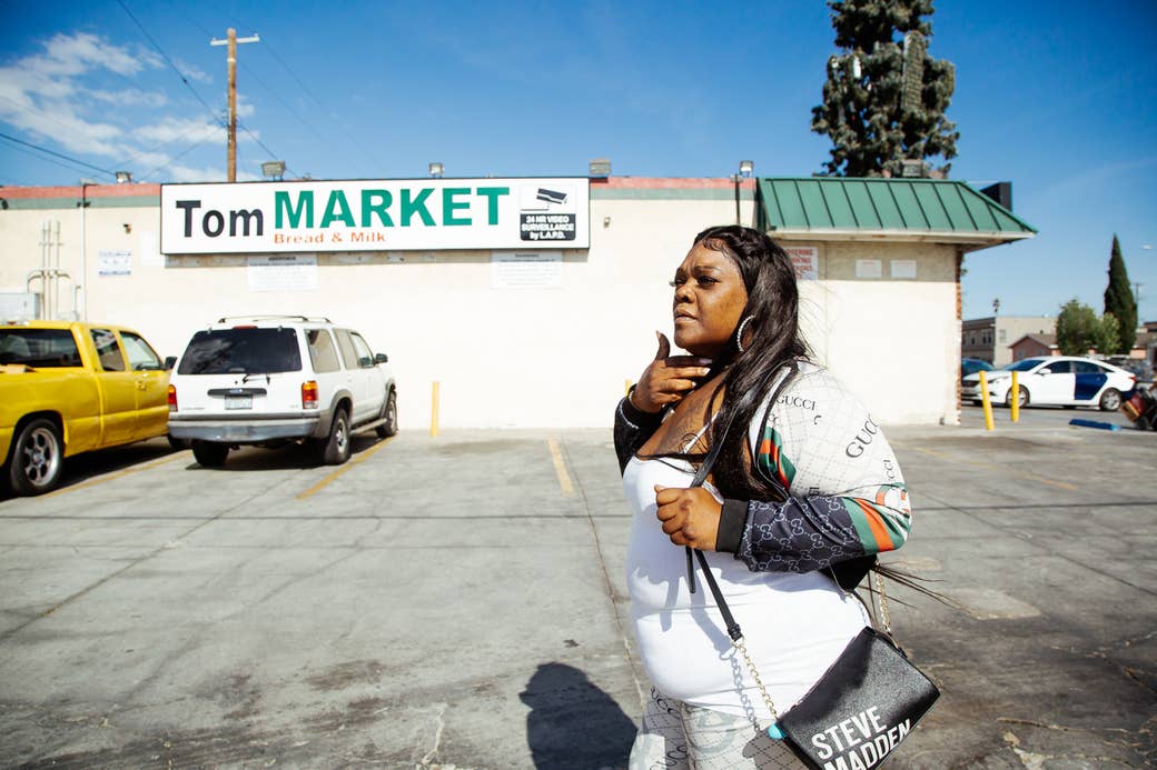 A Black woman with long hair walks in a parking lot