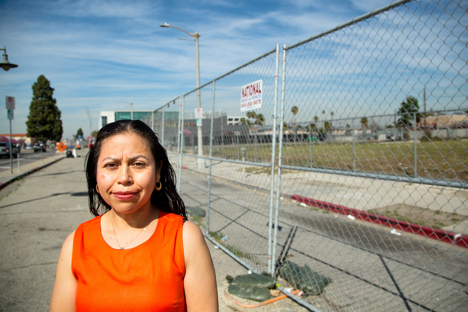 A woman standing in front of barbed-wire fencing looks into the camera