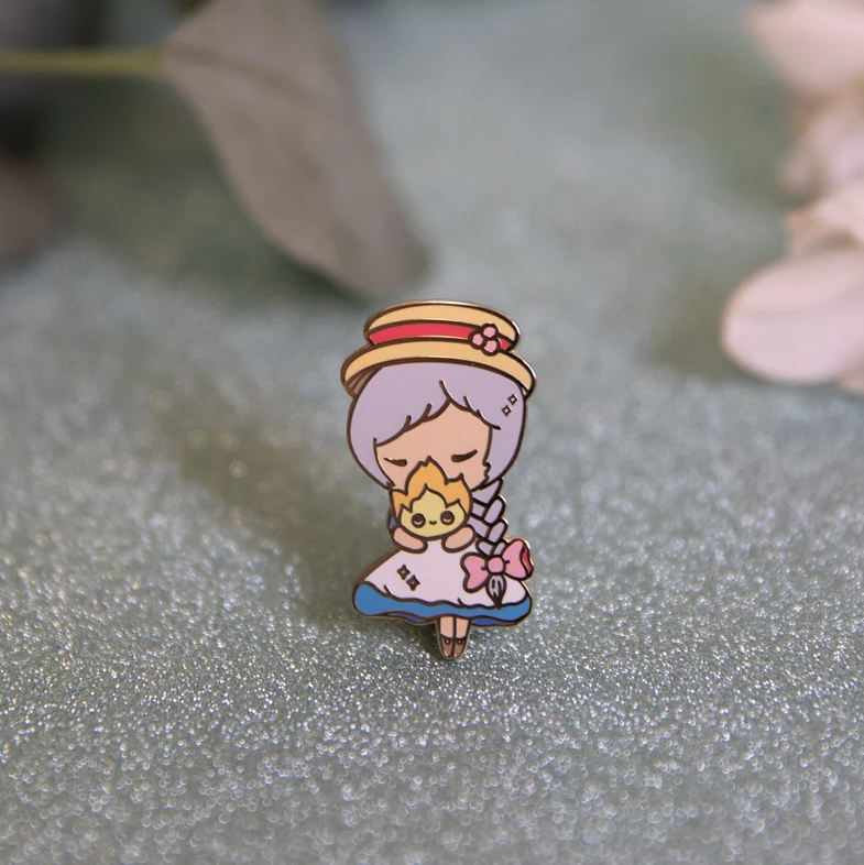 Enamel pin of Sophie from Howl&#x27;s Moving Castle holding Calcifer (flame)