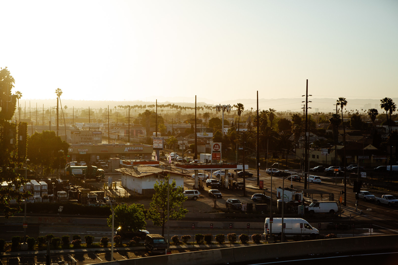 Parking lots, cars, and businesses lit by a low sun