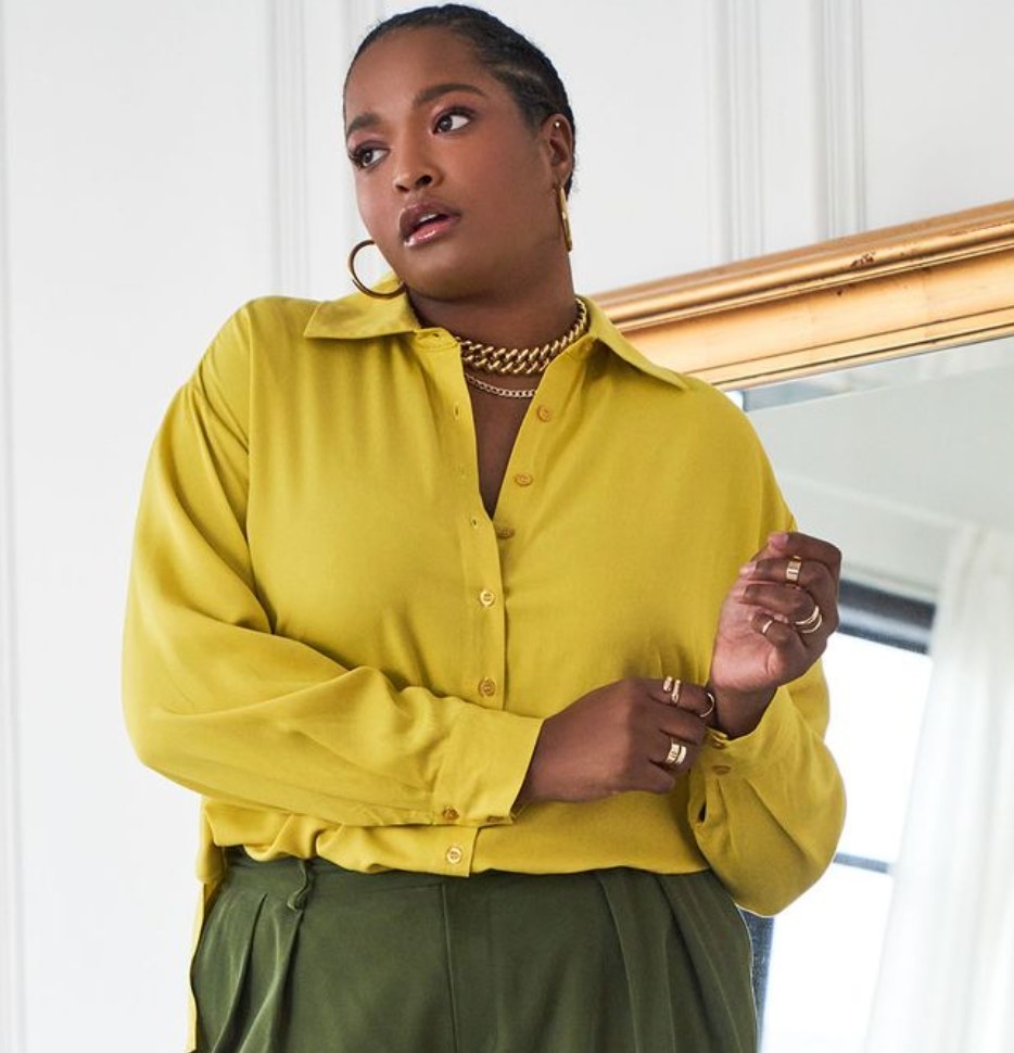 Model is wearing a yellow button-down top with green pants