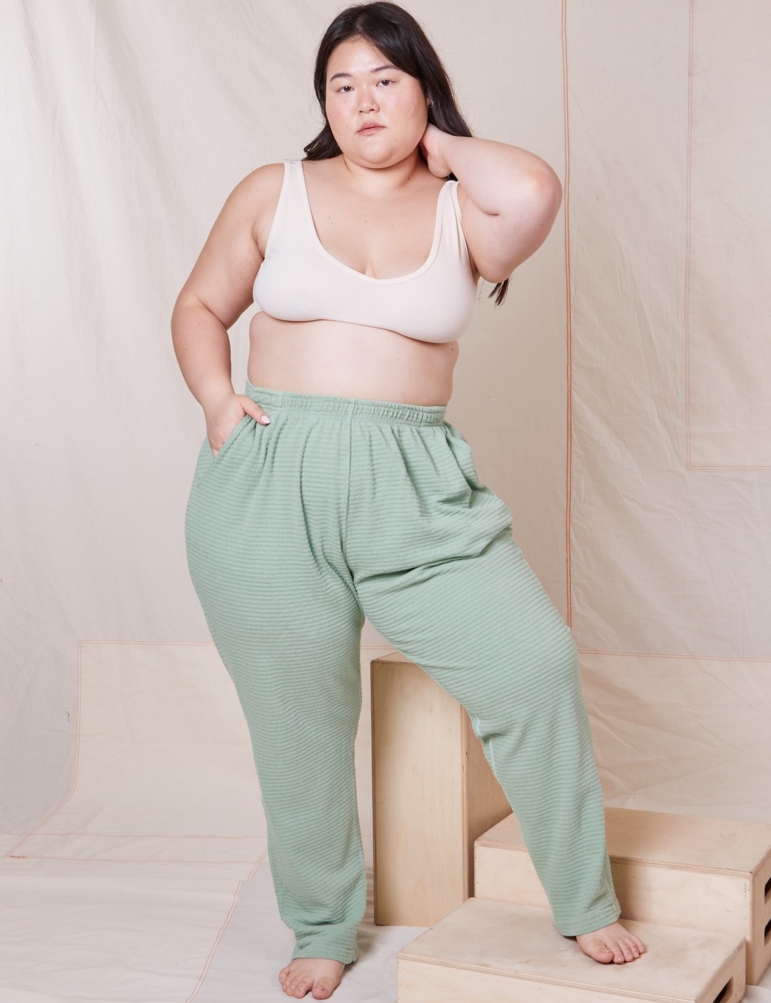 Model is wearing sage green pants and a white bra
