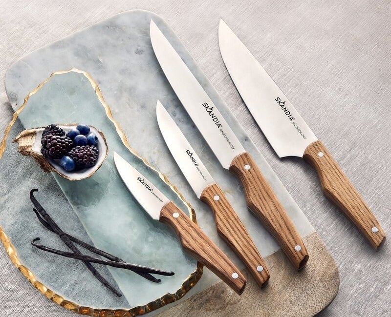 the silver knives with wooden handles on a set of decorative cutting boards