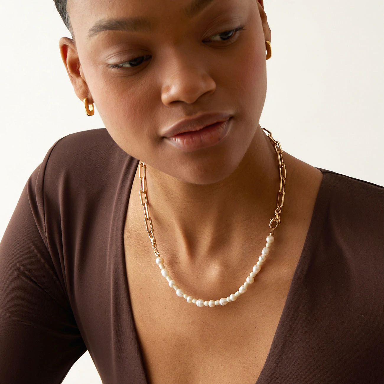 A person wearing a half pear half gold chain necklace