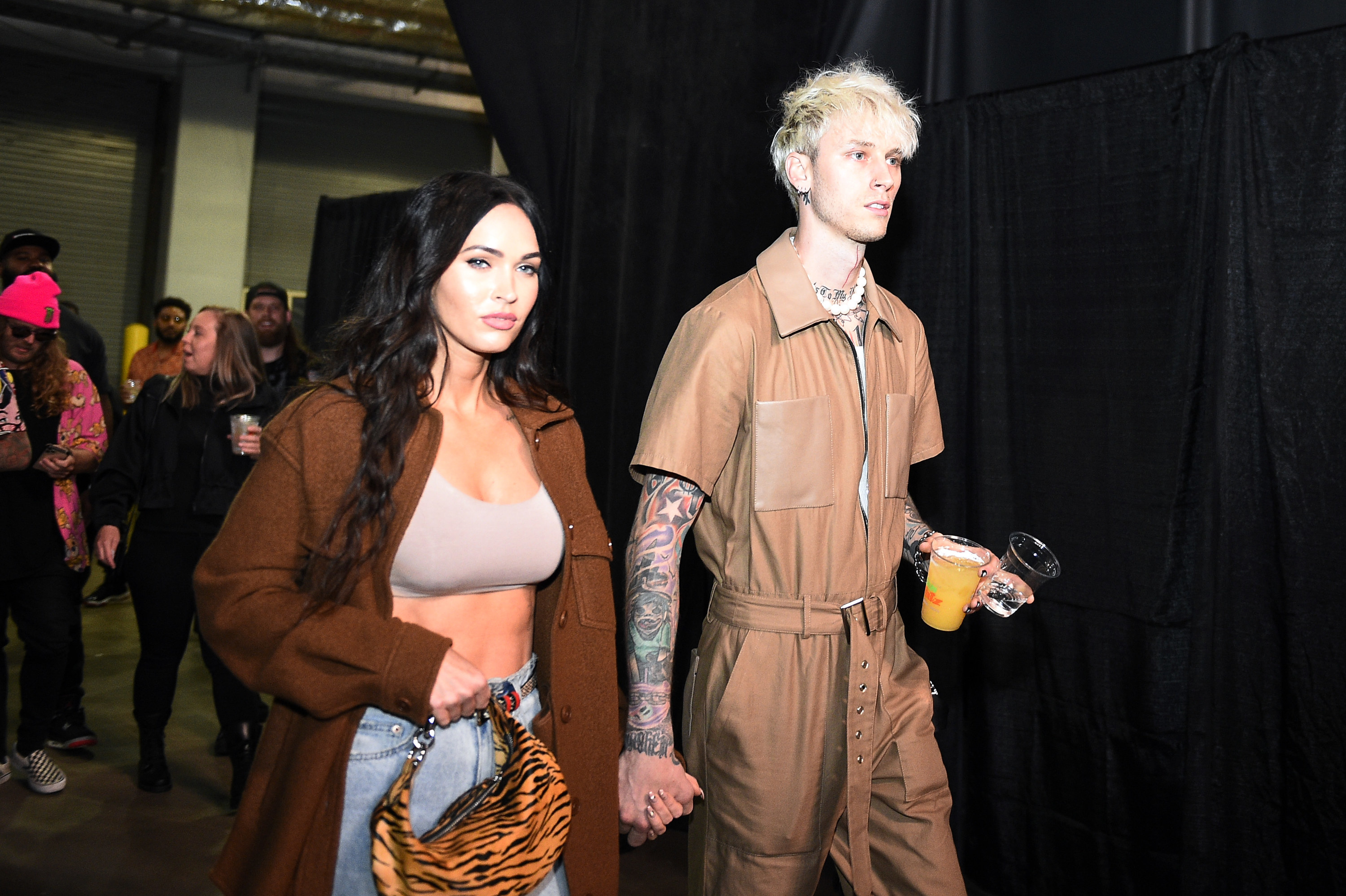 Megan and MGK walk backstage at an event holding hands
