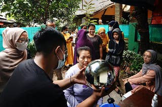 A group of people gathers around a man holding a silvery sphere