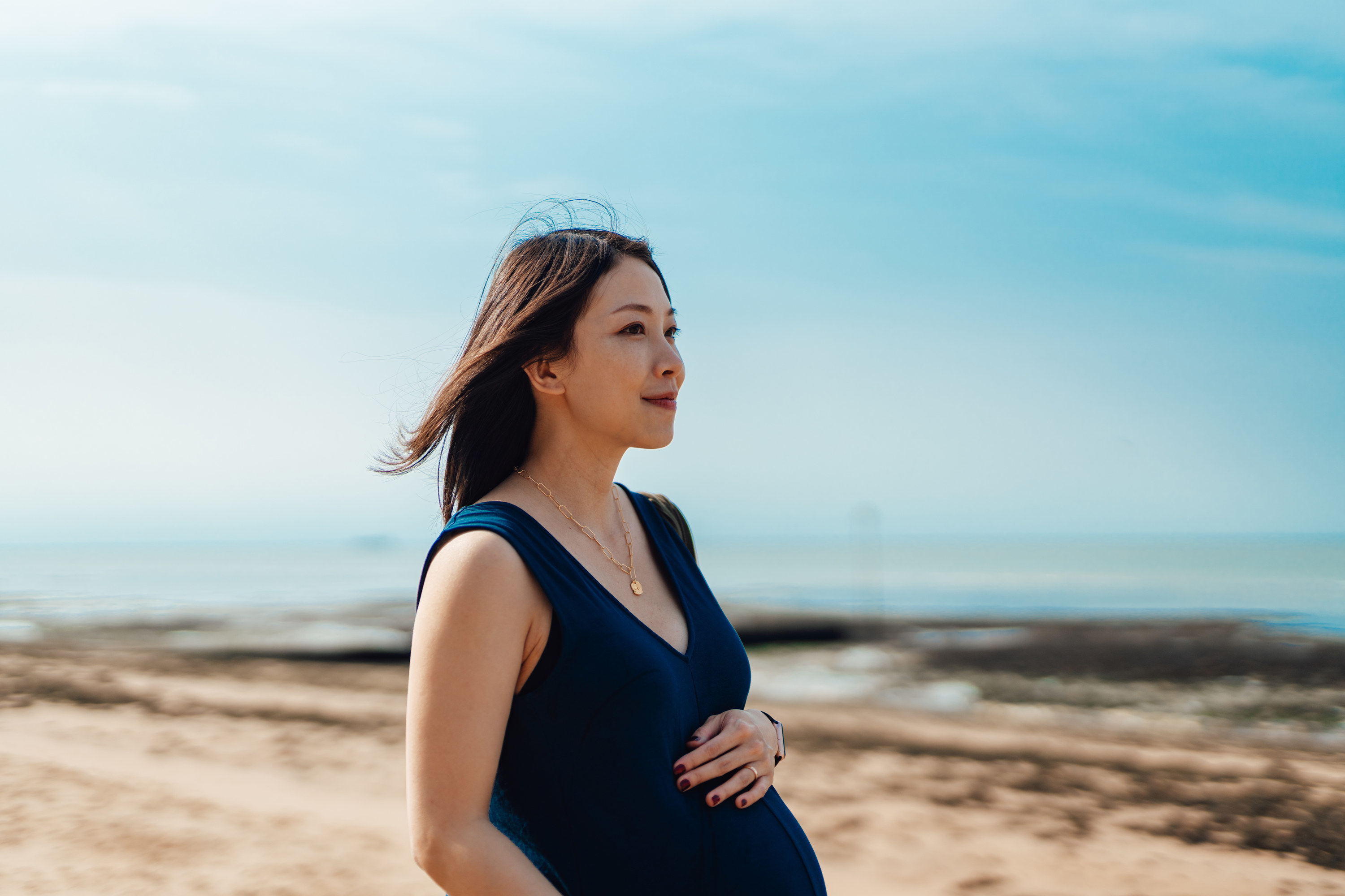 A pregnant woman holding her belly while walking outside