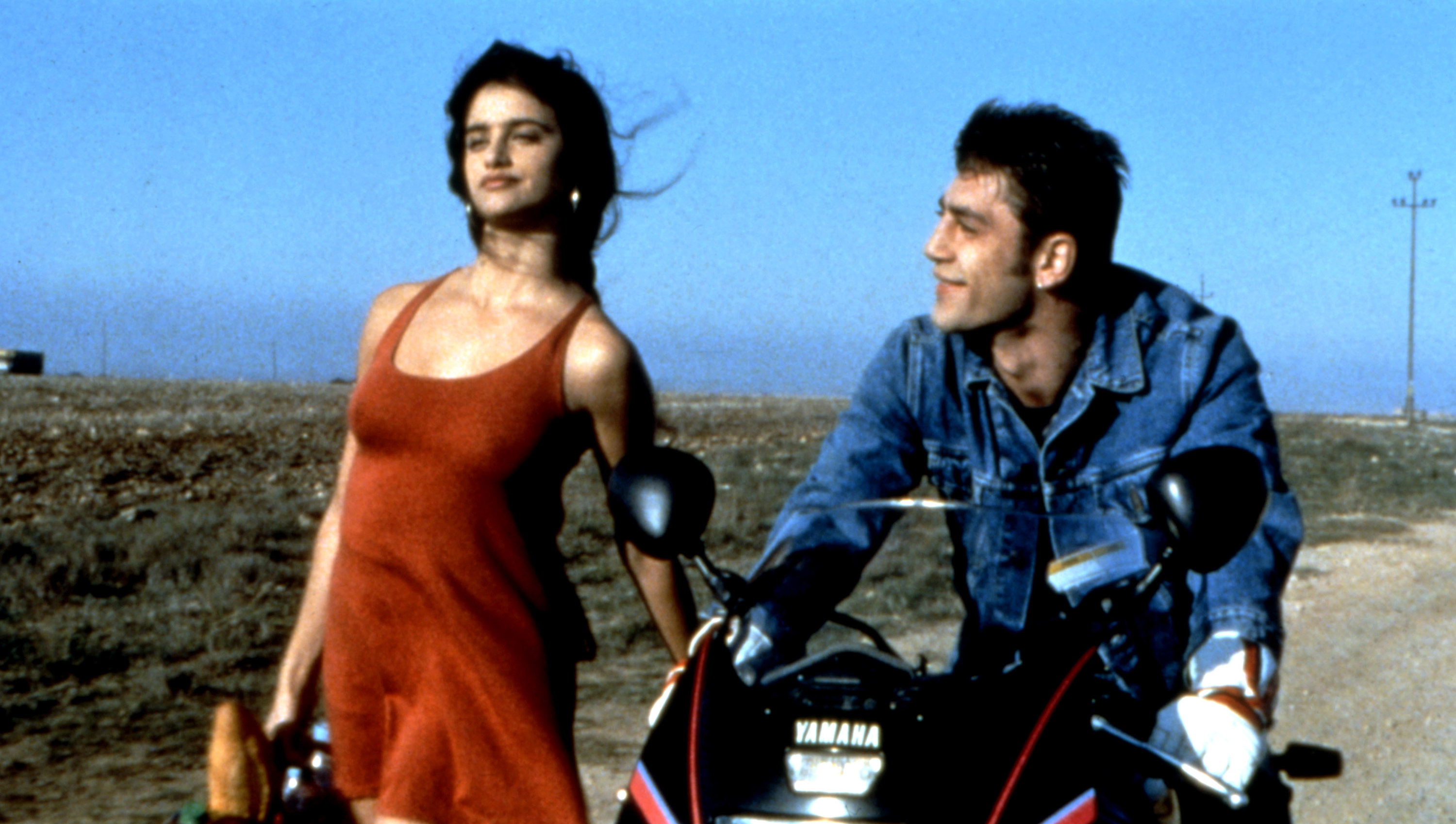 Silvia walks alongside Raul driving a motorcycle